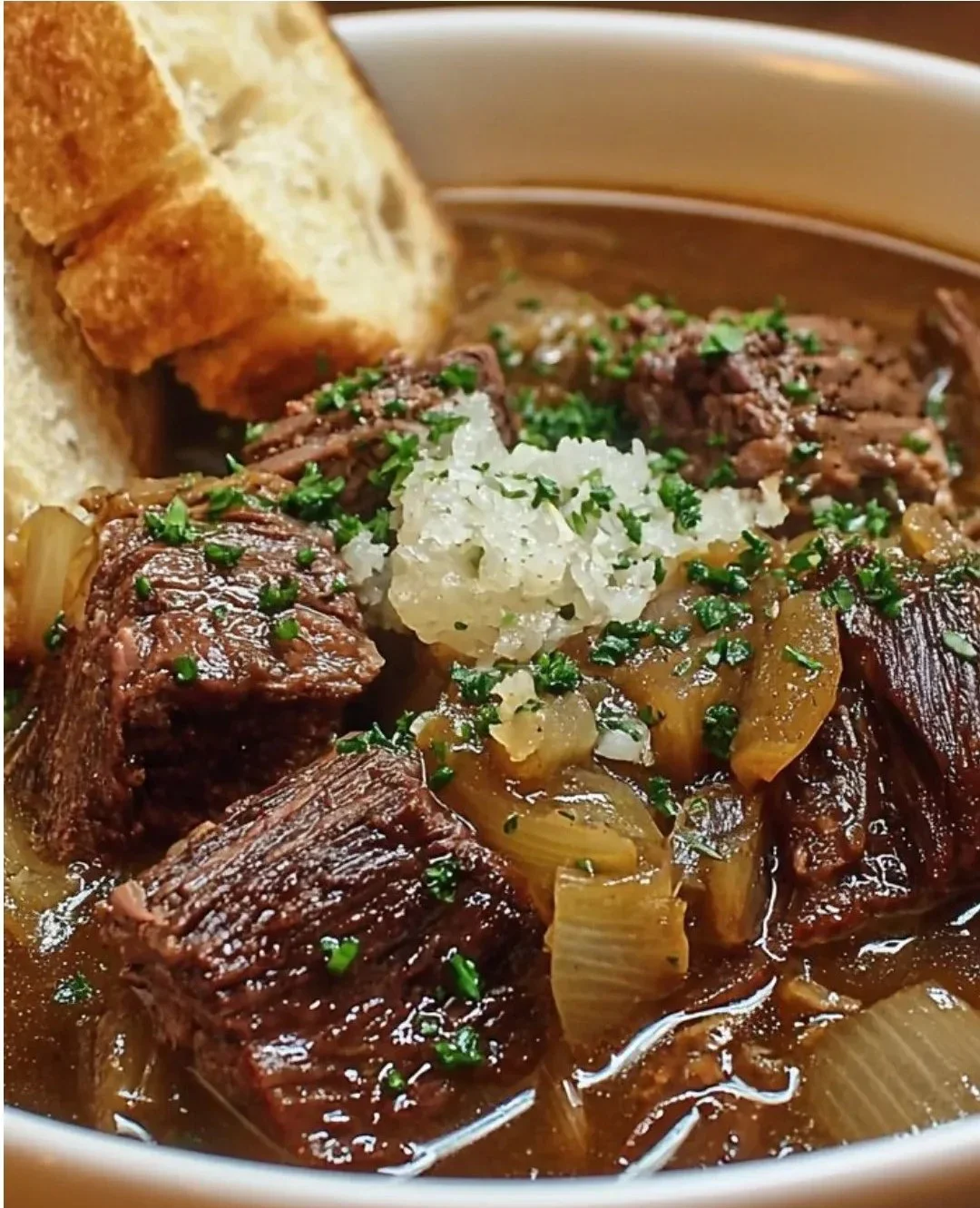 Bowl of French Onion Beef Short Rib Soup garnished with melted cheese and herbs