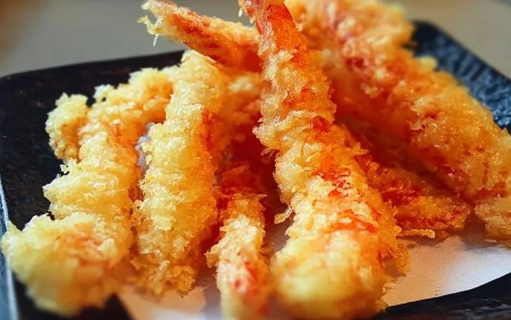 Delicious shrimp tempura served with dipping sauce and garnish.
